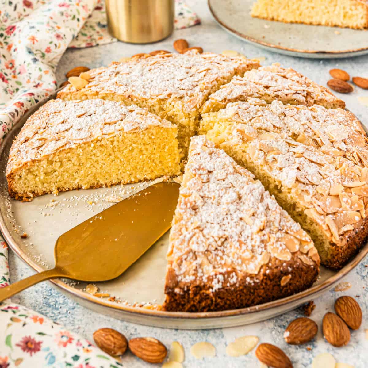 square image of italian almond cake cut into slices on a plate with a cake server