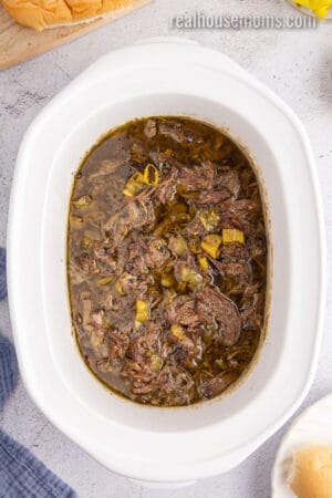 shredded italian beef in a slow cooker with the cooking liquid