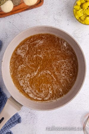 beef broth poured into a skillet with fond from searing a chuck roast