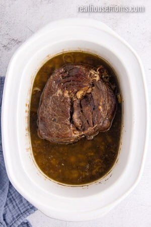 cooked italian beef in a slow cooker with the cooking liquid