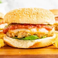 close up of an italian chicken burger on a wooden board