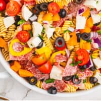 looking down at italian pasta salad in a white serving bowl with recipe name at the bottom