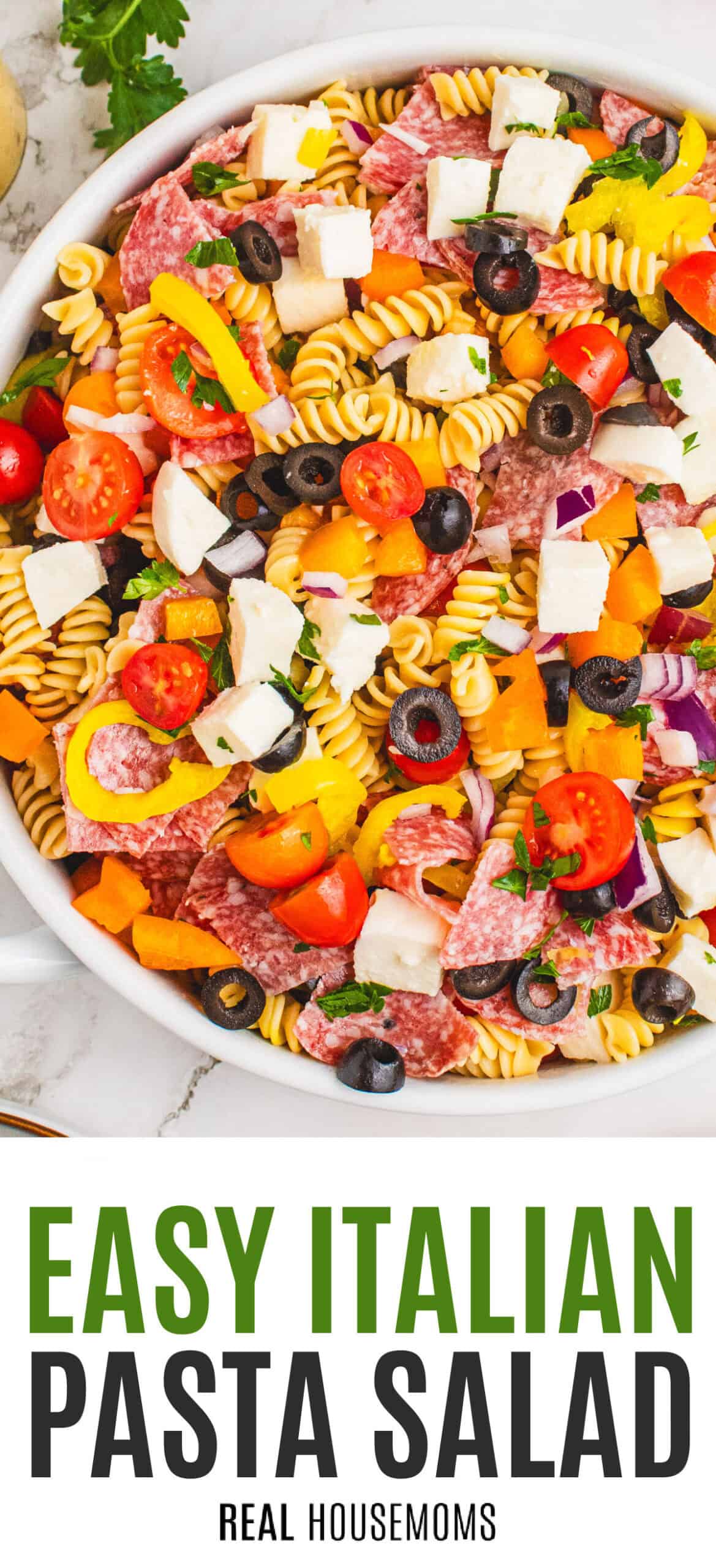 looking down at italian pasta salad in a white serving bowl with recipe name at the bottom