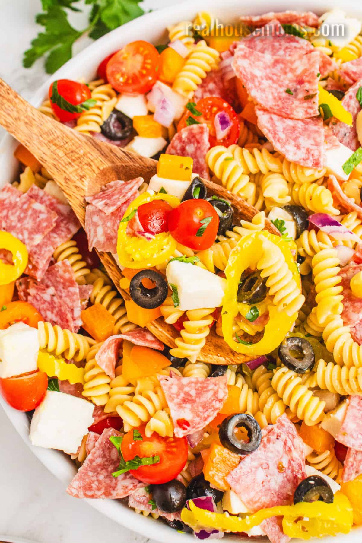 spoonful of italian pasta salad being taken from the serving bowl