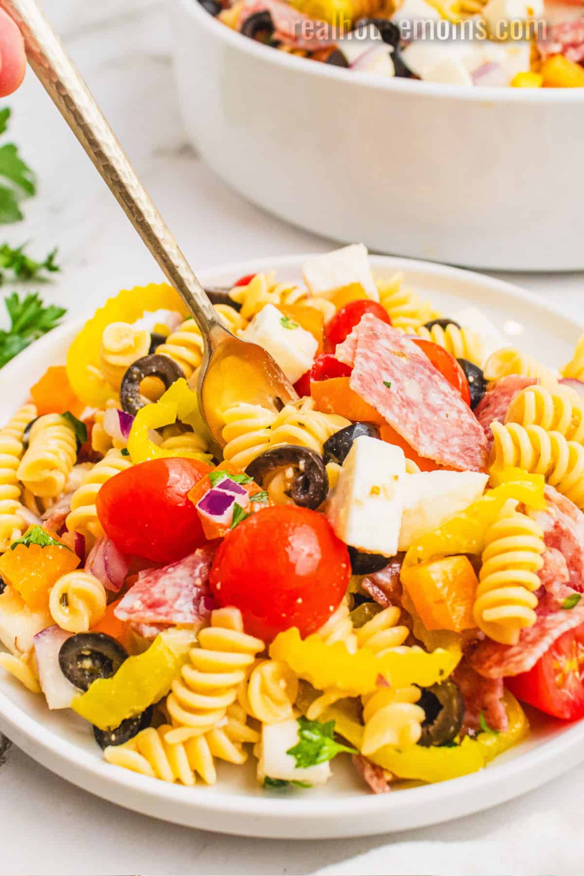 forking being put into a portion of italian pasta salad on a small plate