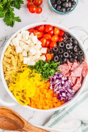 italian pasta salad ingredients in a large white serving bowl