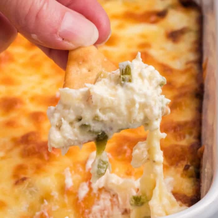 square image of a pita chip dipped into jalapeno crab dip