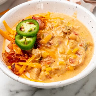 square image of jalapeno popper chicken chili topped with jalapeno slices and bacon in a bowl