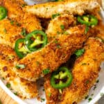 square image of jalapeno ranch chicken tenders on a platter with chopped parsley and jalapeno slices