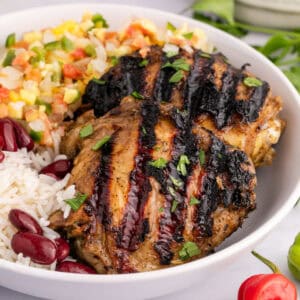 square image of jerk chicken in a bowl with peas & rice and succotash