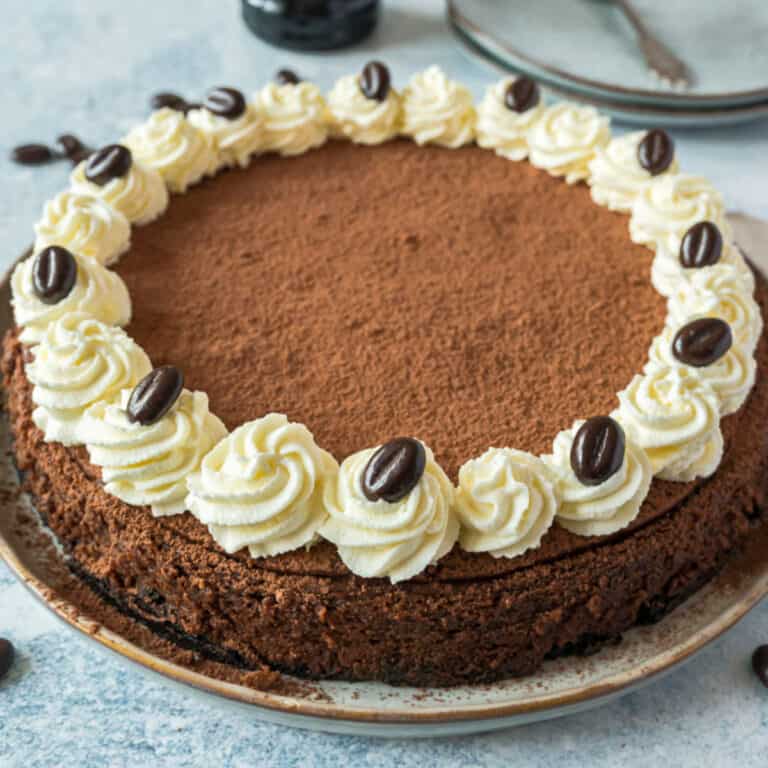 square image of kahlua cheesecake with whipped cream and chocolate-covered espresso beans for garnish