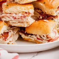 image of a stack of kentucky hot brown sliders on a white plate with the title of the post on the bottom in blue and black lettering