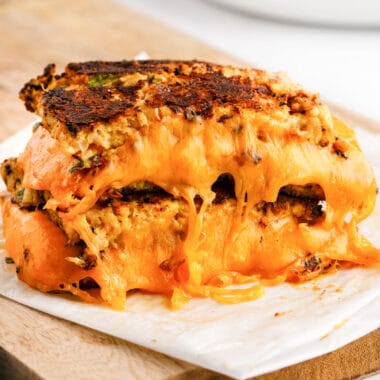 square image of cauliflower grilled cheese halves stacked to show melty cheese