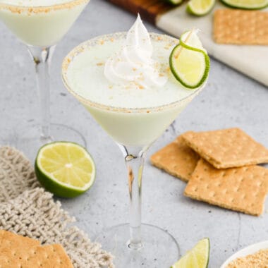 square image of a key lime pie cocktail with whipped cream and a lime wheel