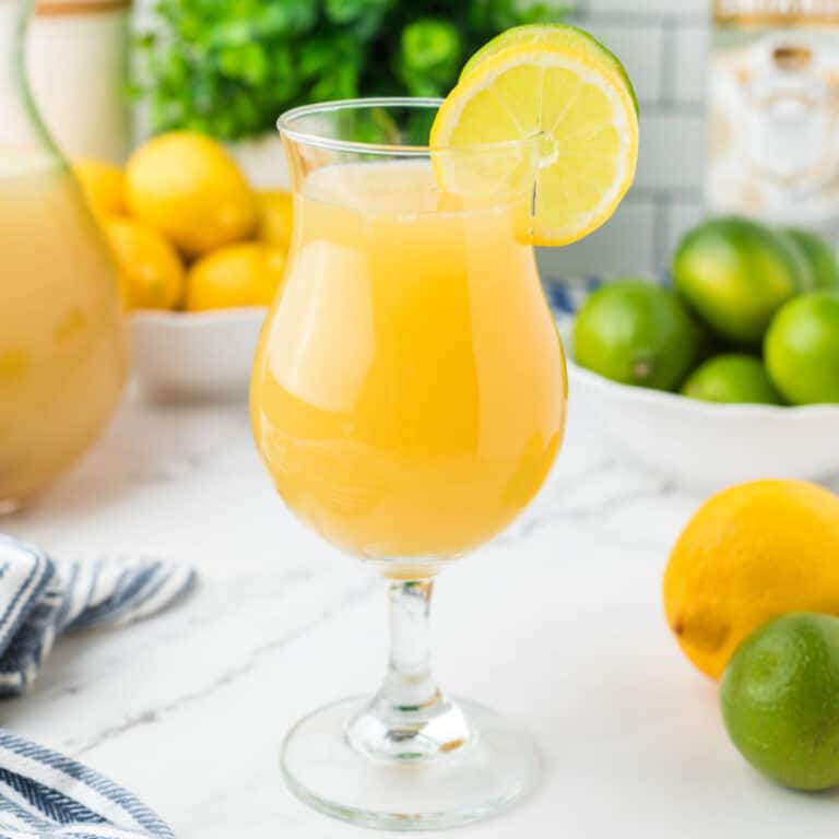 square image of key lime whipped lemonade in a cocktail glass with lemon and lime garnish