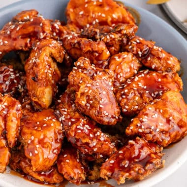 square image of a bowl of korean fried chicken topped with sesame seeds