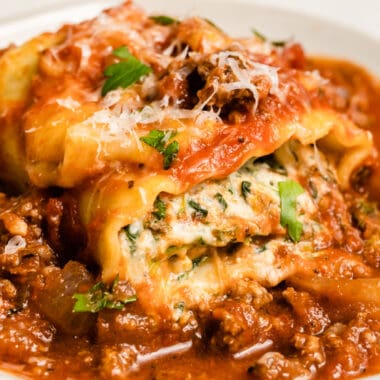 square image of a lasagna rol up on a plate with meat sauce
