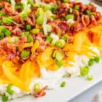 square image of side view of layered bacon ranch dip on a plate