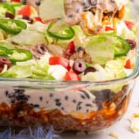spoonful of layered taco salad over the dish with recipe name at the bottom