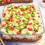 square image of layered taco salad in a baking dish showing the layers