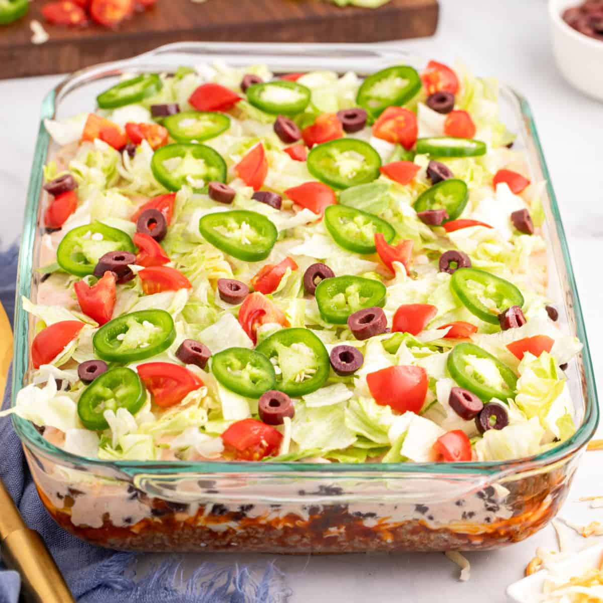 square image of layered taco salad in a baking dish showing the layers
