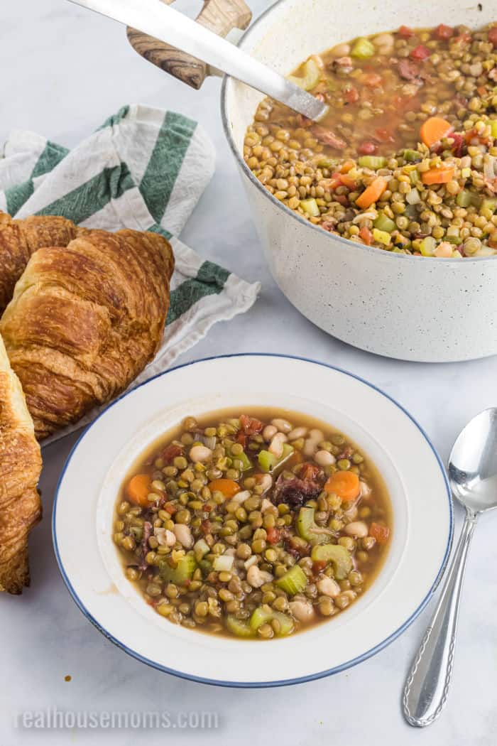 bowl of leftover ham soup with lentils with croissants and a spoon