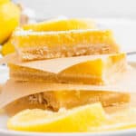 square image of lemon bars stacked up with parchment paper between the bars