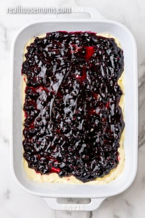 blueberry pie filling spread over lemon mousse in a baking dish