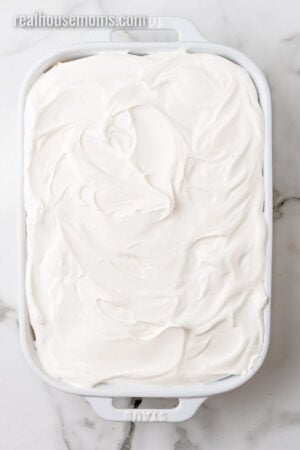 cool whip spread all over the over a lemon blueberry icebox cake in a baking dish
