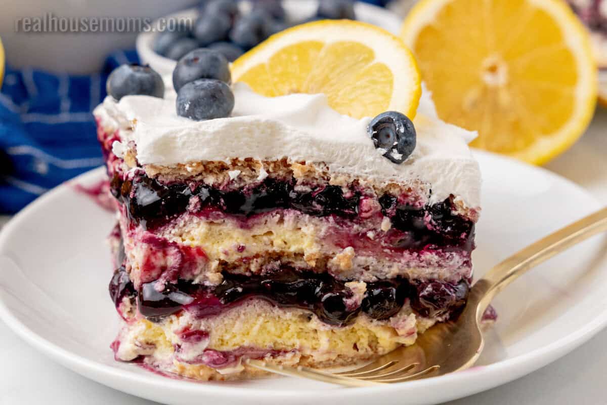 side view of slice of lemon blueberry icebox cake on a plate with a fork showing all the layers