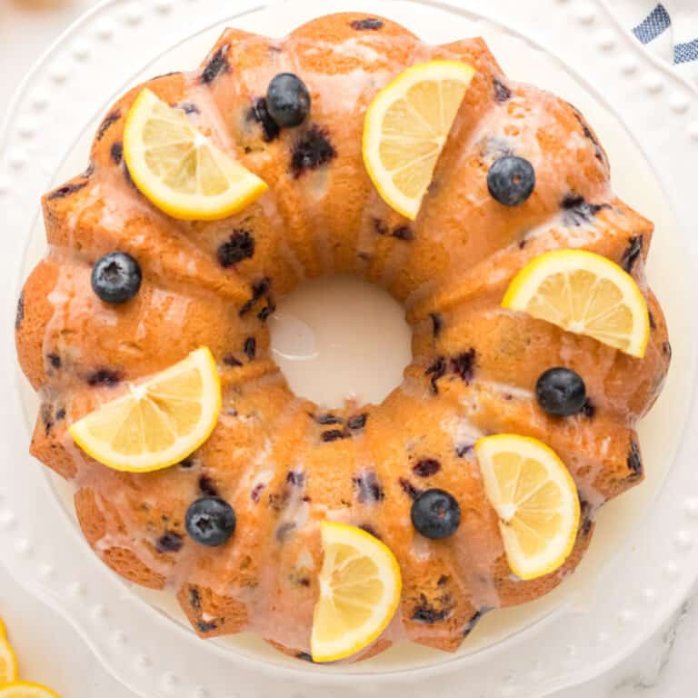 square image looking down at a lemon blueberry pound cake topped with lemon slices and blueberries