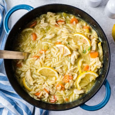 square image of lemon chicken orzo soup in a pot with a ladle