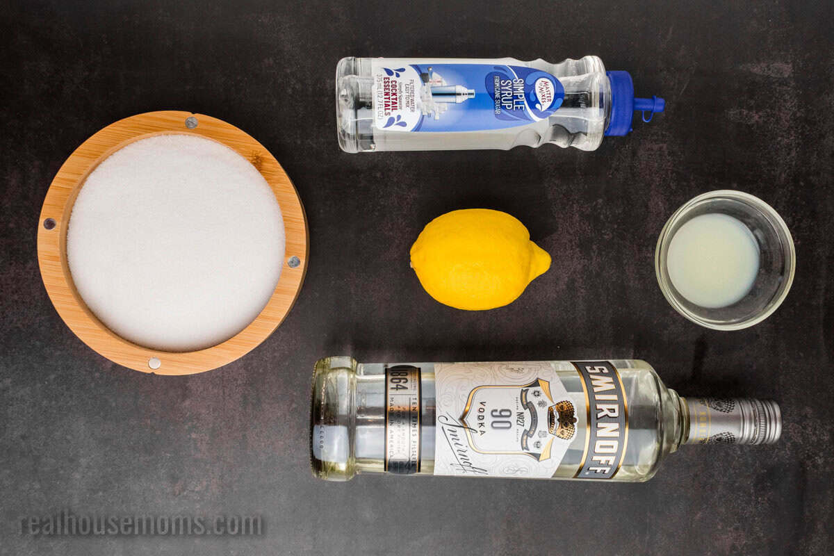 ingredients to make a lemon drop martini on a black counter