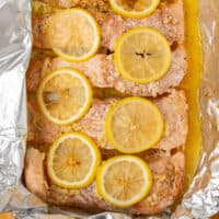 baked lemon garlic butter baked salmon with lemon slices in foil with recipe name at the bottom