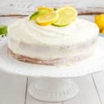 square image of lemon-lime layer cake on a cake stand with lemon and lime slices arranged on top