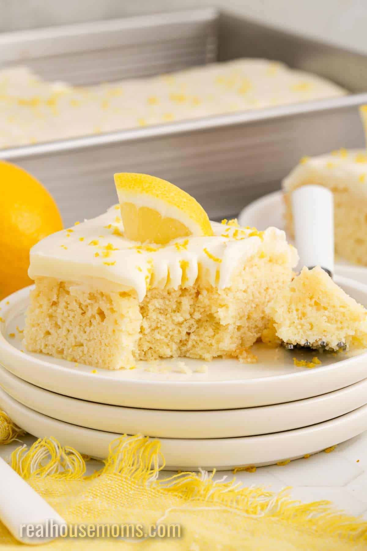 bite of lemon poke cake on a fork next to the slice of cake on a plate