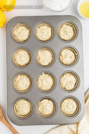 lemon poppy seed muffin batter spooned into lined muffin tin cups