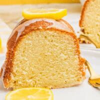 close up bite of lemon pound cake on a fork resting on a small plate next to the slice