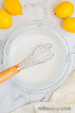 lemon glaze in a glass bowl after being whisked with the whisk still in the bowl
