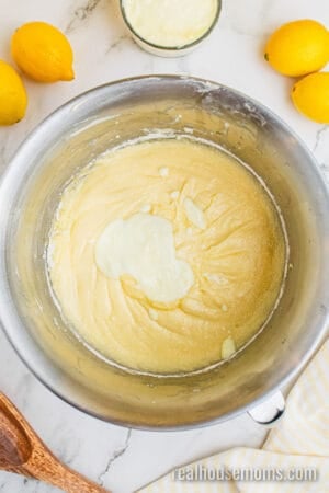 greek yogurt added to a stand mixer bowl of lemon pound cake batter