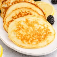 lemon ricotta pancakes layered on a platter with recipe name at the bottom