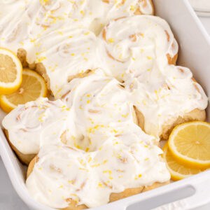square image of lemon rolls in a baking dish with lemon slices