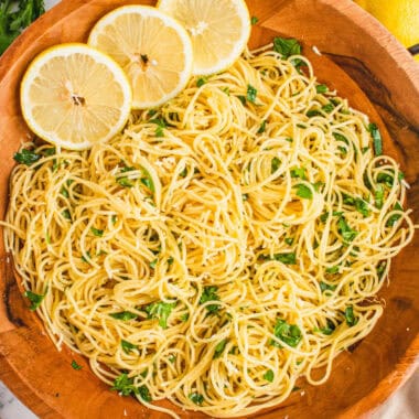 square image of lemon spaghetti in a wooden serving bowl with lemon slices