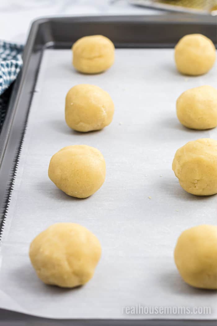 cookie dough rolled into balls on a baking sheet with parchment paper