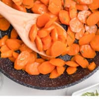 Liz's candied carrots in a skillet with a wooden spoon with recipe name at the bottom