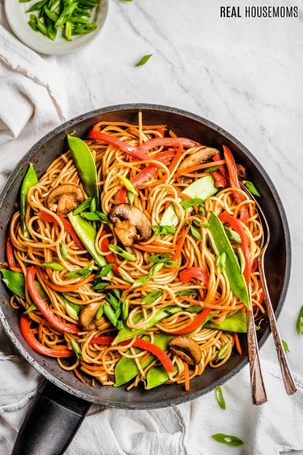 skillet of lo mein garnished with sliced green onions