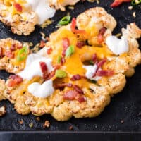 square close up image of a loaded cauliflower steak on baking