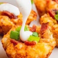 ranch dressing being poured onto loaded tater tot bites topped with green onions with the title of the post on top in red and black lettering