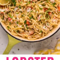 lobster alfredo in a skillet garnished with lemon wedges and parsley with recipe name at the bottom
