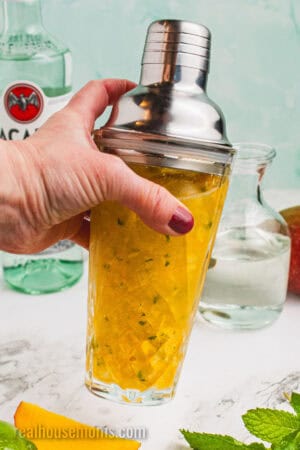 mango puree, rum, simple syrup, and lime juice being shaken in a cocktail shaker with ice